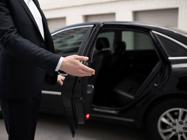 Chauffeur welcoming a passenger and opening the door of a luxury vehicle